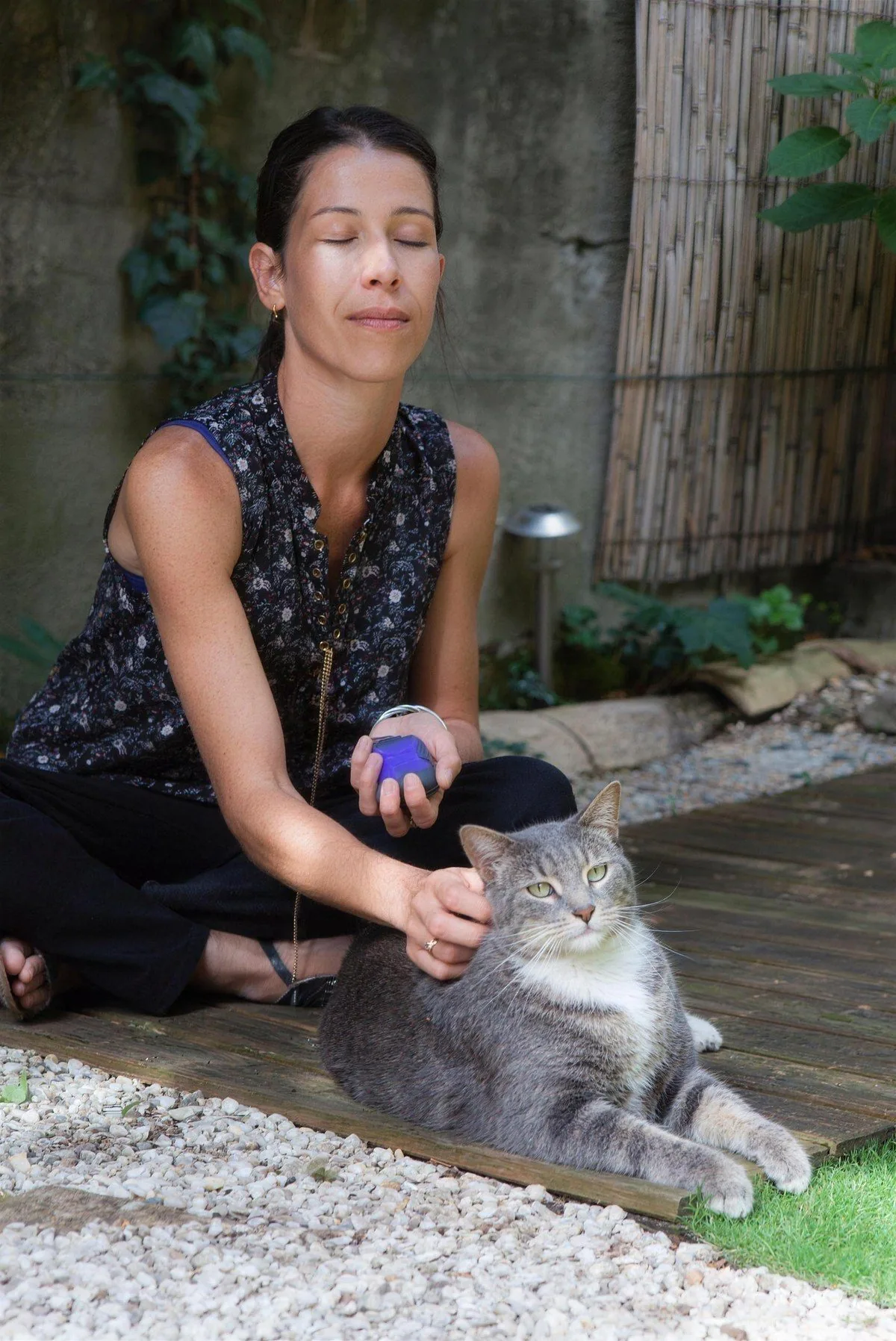 Une femme respire les yeux fermés, le dispositif ZenSpire Pets dans la main, son chat détendu contre elle